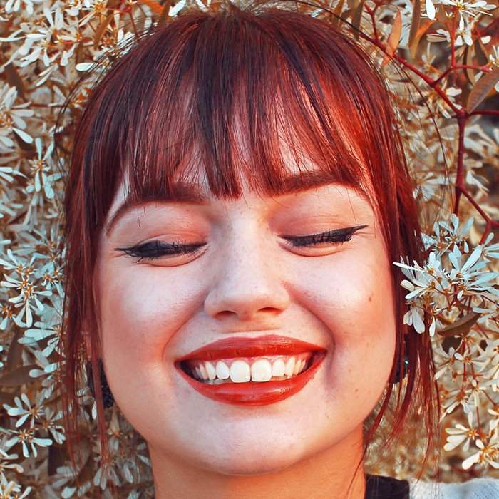 Redhead woman smiling with eyes closed outside dentist office.