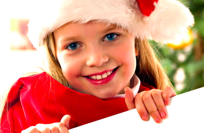 Little girl smiling wearing a santa hat at the dentist.