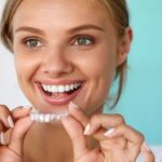 Blonde woman smiling about to put on her clear aligners.