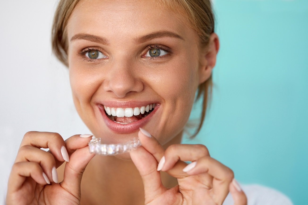 Blonde woman smiling about to put on her clear aligners.