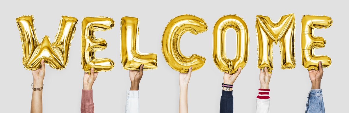 Several hands hold up gold balloons to WELCOME new patients to ADC Dental Group in Joplin, MO