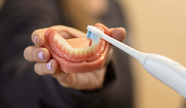 closeup of a person showing how to brush dentures
