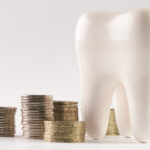 A white tooth next to stacks of coins to indicate an affordable dentist in Joplin, MO