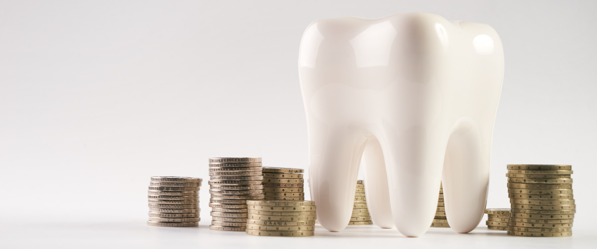 A white tooth next to stacks of coins to indicate an affordable dentist in Joplin, MO