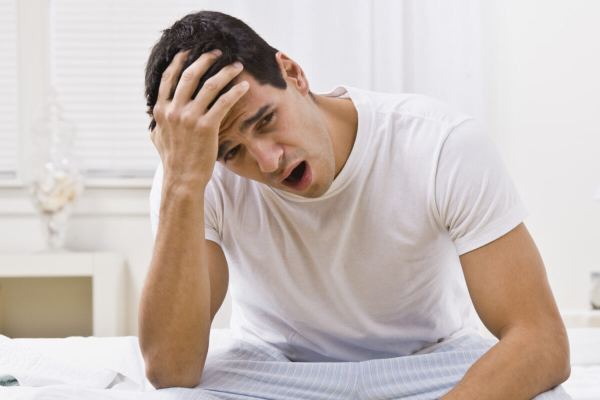 Brunette man yawns after getting out of bed due to daytime drowsiness from sleep apnea