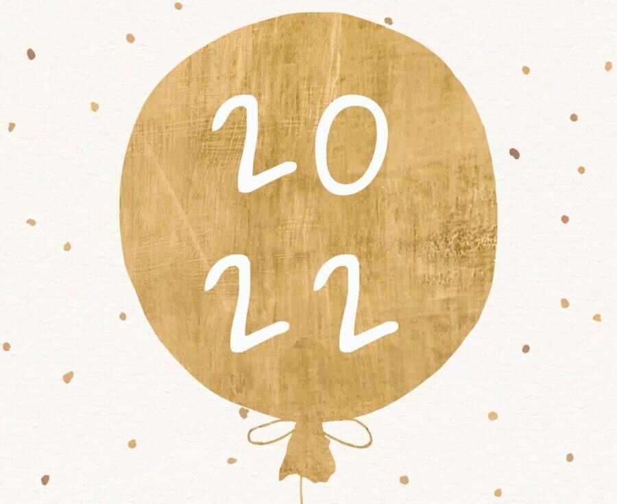 a gold balloon that says 2022 against a beige background with gold polka dots