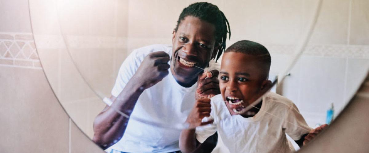 father and young son floss their teeth together