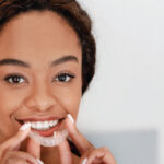 young woman smiles as she inserts her Invisalign clear aligner