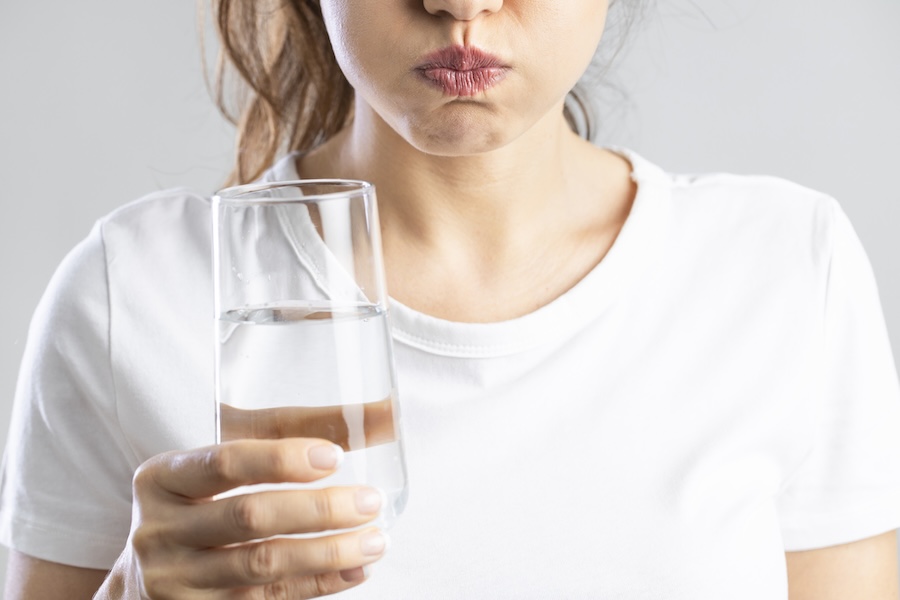 woman with dry mouth drinking water to help symptoms