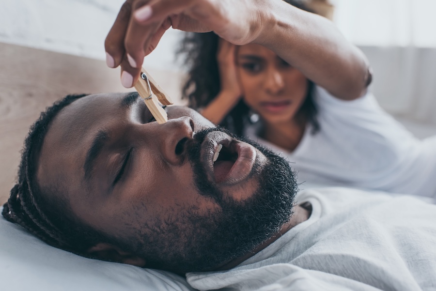 man snoring while partner puts clothespin on nose, sleep apnea