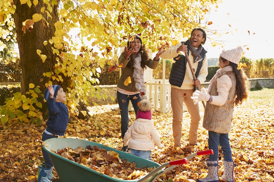 family playing in the leaves before fall dental checkup